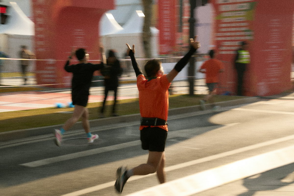 Runner raising both arms as she crosses a race finish line