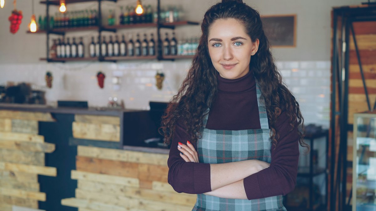 Smiling coffee shop owner standing at her counter